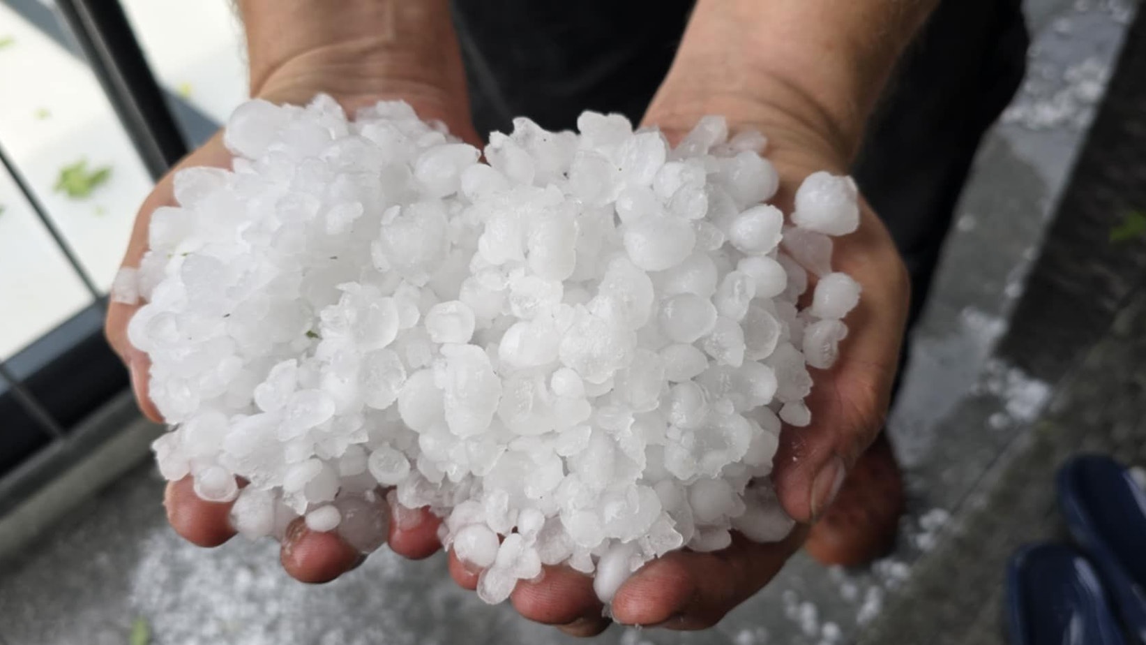 Eine Frau hält Hagelkörner in ihren Händen.