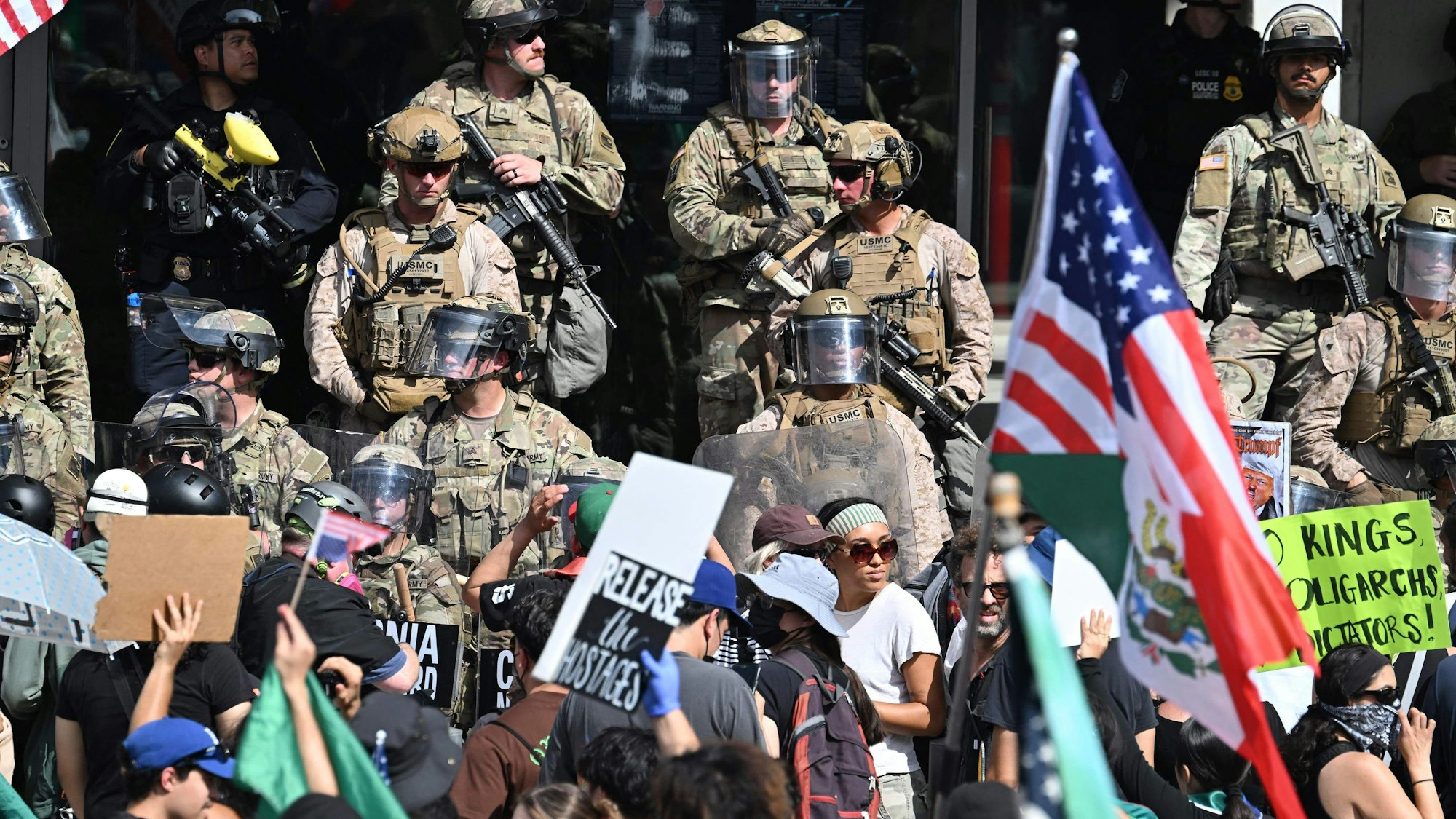 US Marines, California National Guard and Los Angeles Police stand guard on the steps of the Federal Building on June 14, 2025 in Los Angeles, as protesters participating in the "No Kings" demonstration arrived in the area. Tens of thousands of protesters rallied nationwide Saturday against Donald Trump ahead of a huge military parade on the US president's 79th birthday -- as the killing of a Democratic lawmaker underscored the deep divisions in American politics. "No Kings" demonstrators took to the streets in New York, Los Angeles, Chicago, Philadelphia, Houston, Atlanta and hundreds of other cities across the United States to condemn what they call Trump's dictatorial overreach. (Photo by Robyn Beck / AFP)