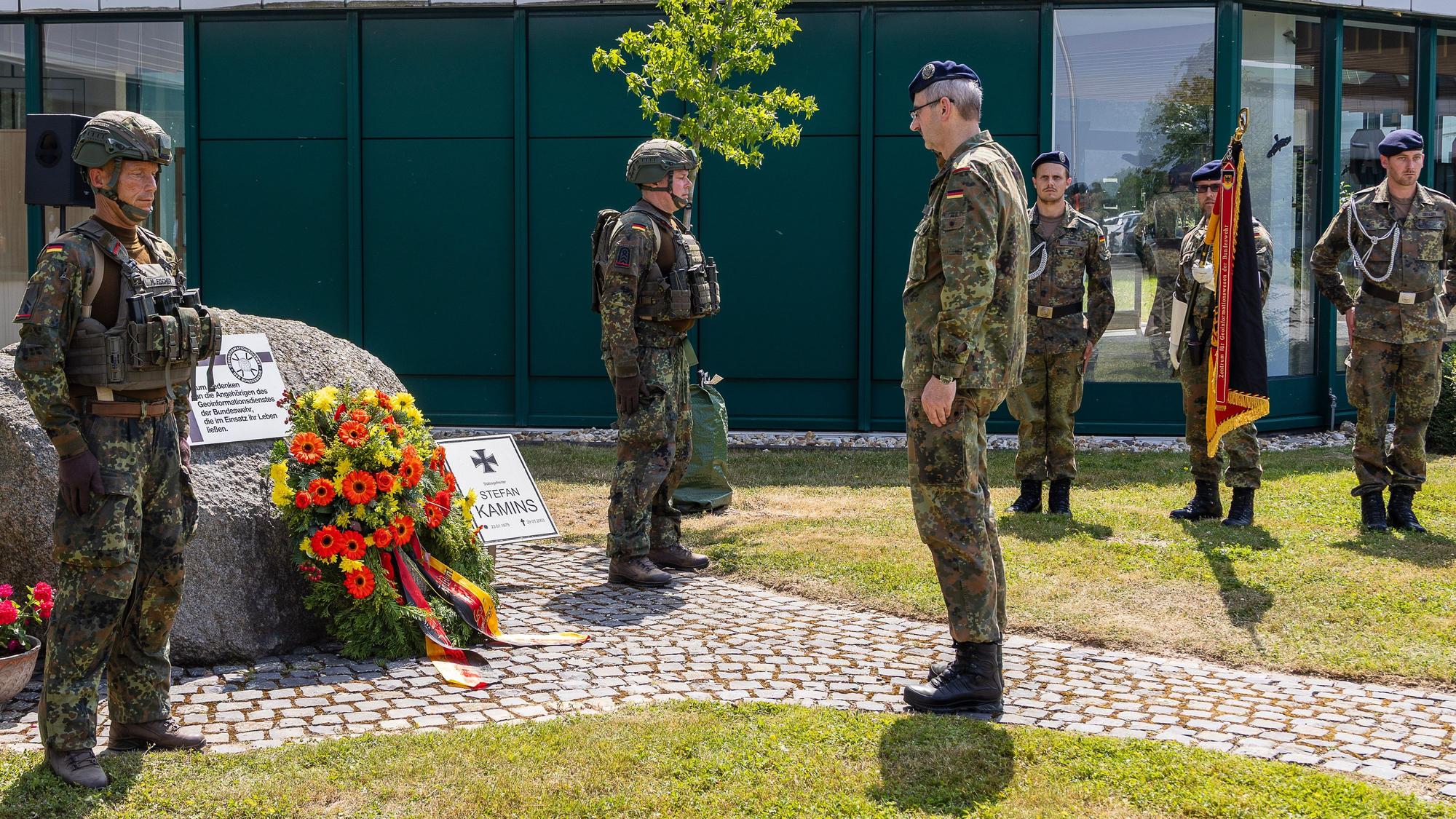 Der Brigadegeneral steht vor dem Stein, an dem die Soldaten den Kranz abgelegt haben. Im Hintergrund steht eine Ehrenwache mit gesenkter Fahne.