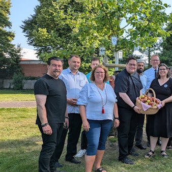 Die Vortragenden und die Organisatoren haben sich zum Foto unter dem Friedensbaum aufgestellt. Im Baum hängen die Symbole der Religionsgemeinschaften.