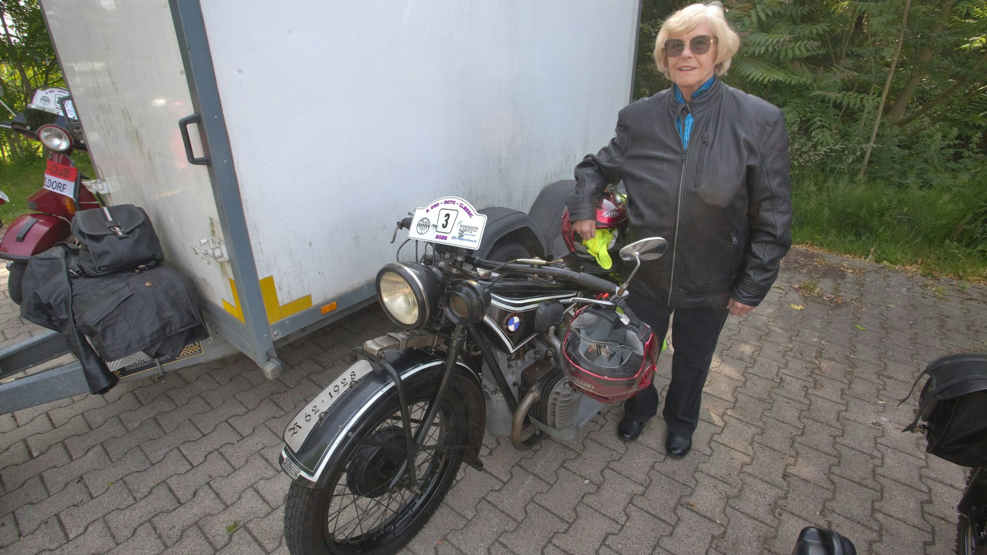 Eine Frau steht neben einem Motorrad.