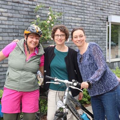 Drei Frauen stehen mit ihren Fahrrädern beisammen.
