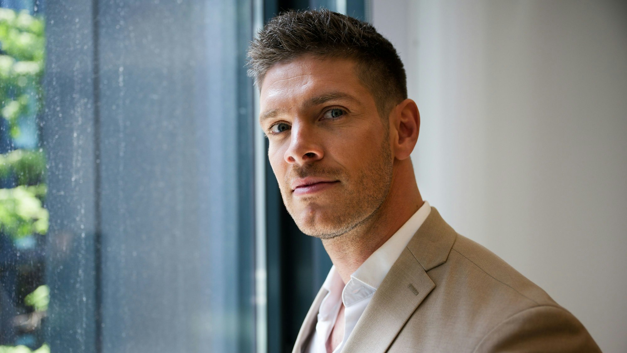 „Bachelor“ Martin Braun schaut in Richtung der Kamera, links von ihm ein verregnetes Fenster.