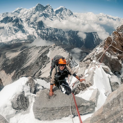 Frederik Tepe beim Aufstieg, hinter ihm ist ein atemberaubendes Bergpanorama zu sehen.
