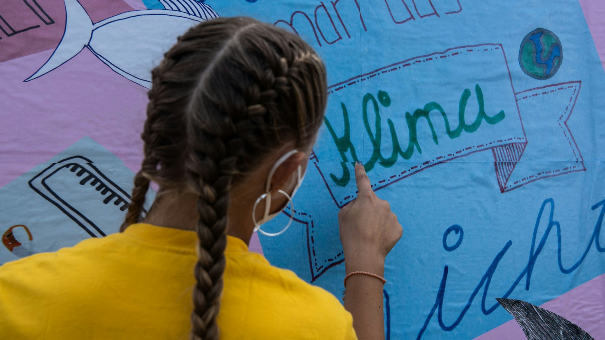 Eine junge Umweltaktivistin plakatiert ein Wahlplakat vor dem Reichstag in Berlin.