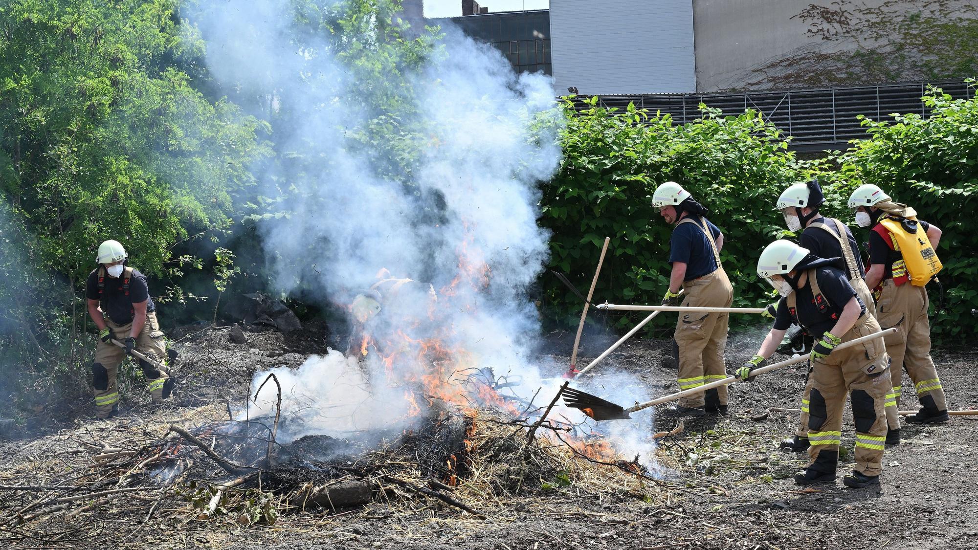 Feuerwehrleute löschen mit Feuerpatschen und einem Waldbrandrucksack einen Vegetationsbrand im Rahmen einer Übung auf dem Zanders-Gelände in Bergisch Gladbach.