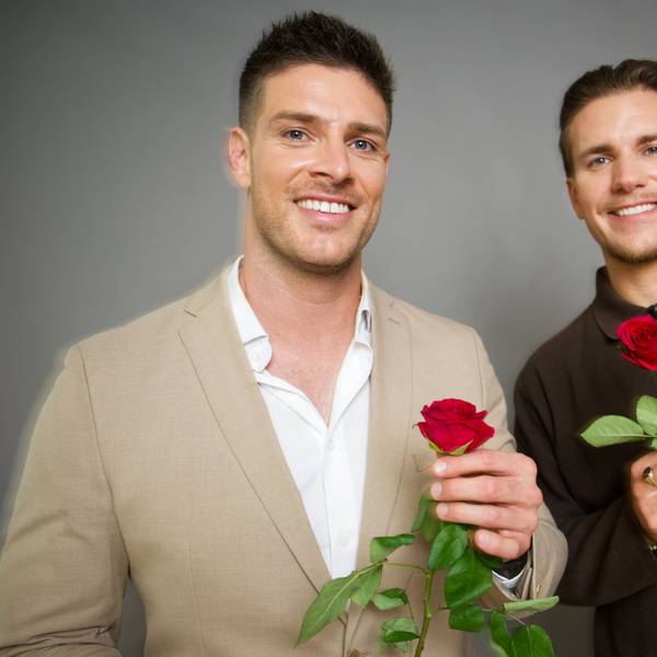 Die neuen „RTL-Bachelors“ Martin Braun (l.) und Felix Stein (r.) halten Rosen in der Hand und lächeln vor einer Wand stehend in Richtung Kamera.