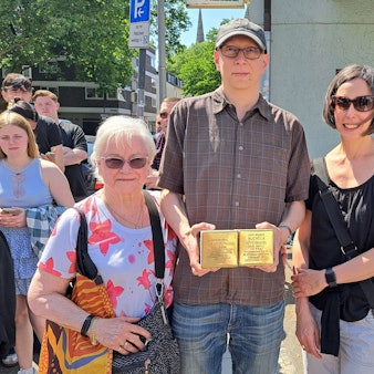 Zwei Frauen und ein Mann (Mitte) stehen nebeneinander. Der Mann hält zwei Stolpersteine in seinen Händen.
