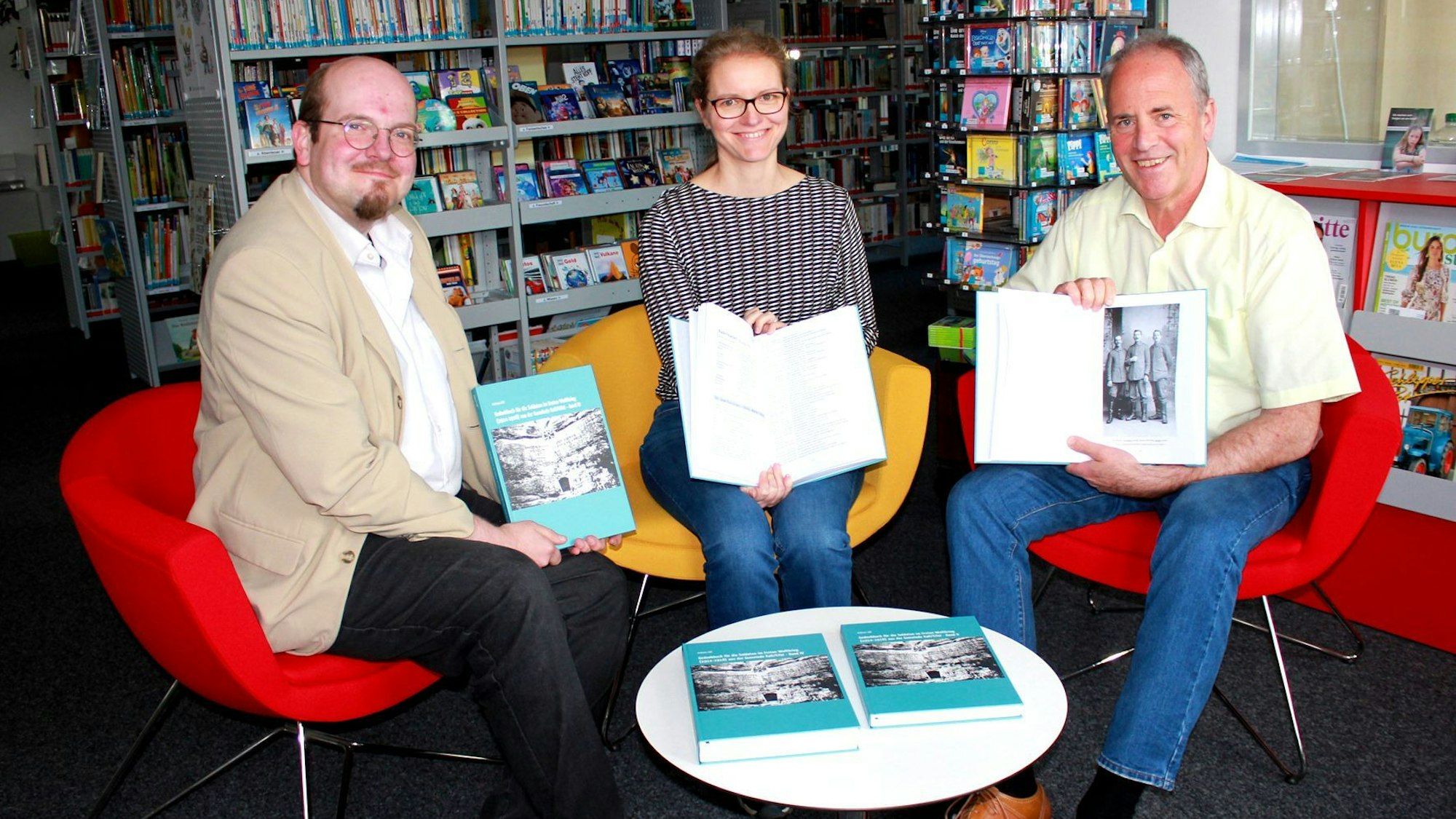 Andreas Züll, Nicole Gutmann und Hermann-Josef Esser sitzen auf Sesseln an einem Tisch nebeneinander und präsentieren jeweils ein Buch.
