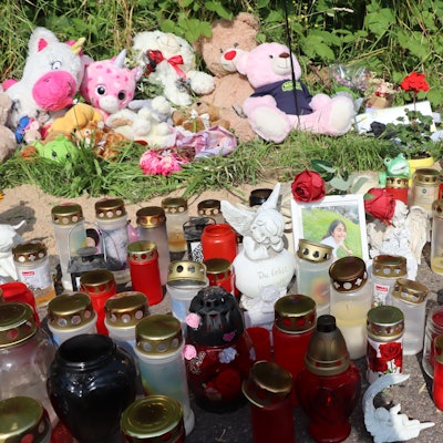 Auf dem Bild sehen Sie ein Denkmal mit vielen Kerzen, weichen Spielzeugen und Souvenirfotos.