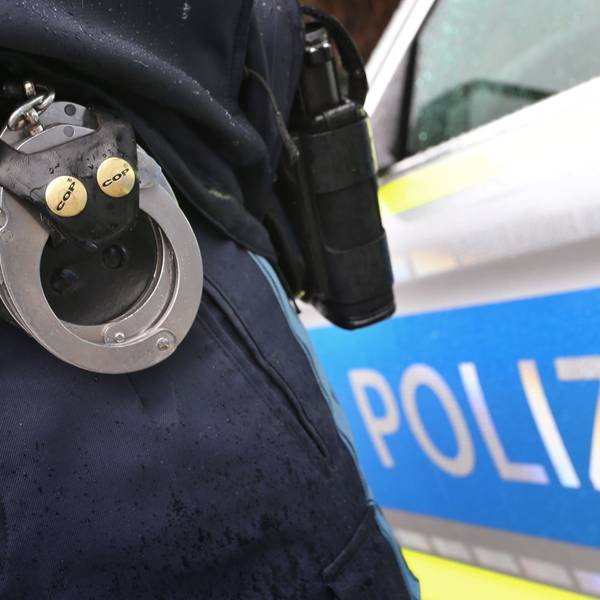 ARCHIV - 15.03.2019, Bayern, Kempten: ILLUSTRATION - Ein Polizist mit Handschellen und einer Pistole am Gürtel steht vor einem Streifenwagen. (zu dpa: «Einbrecher fragt Polizisten nach Weg - Festnahme») Foto: Karl-Josef Hildenbrand/dpa +++ dpa-Bildfunk +++
