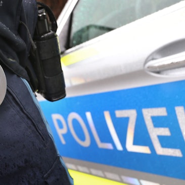 ARCHIV - 15.03.2019, Bayern, Kempten: ILLUSTRATION - Ein Polizist mit Handschellen und einer Pistole am Gürtel steht vor einem Streifenwagen. (zu dpa: «Einbrecher fragt Polizisten nach Weg - Festnahme») Foto: Karl-Josef Hildenbrand/dpa +++ dpa-Bildfunk +++