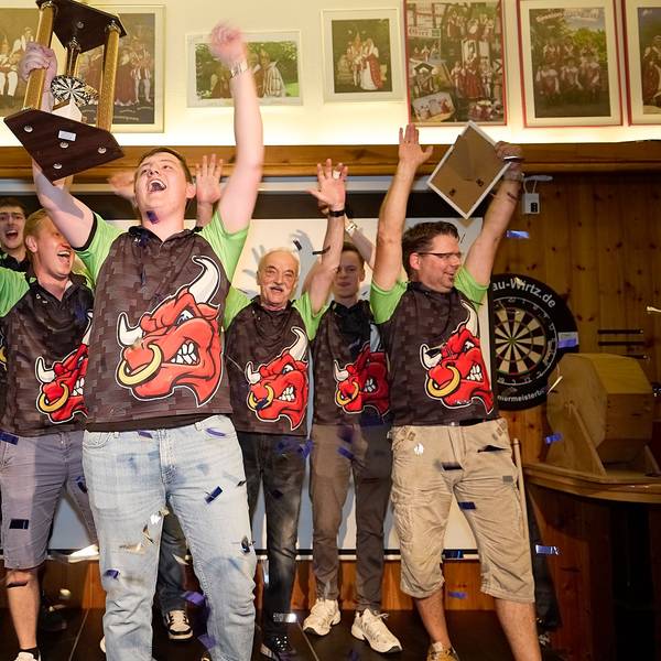 Sieben Männer reißen die Arme hoch, einer hält einen Pokal, einer anderer eine Urkunde in die Luft.
