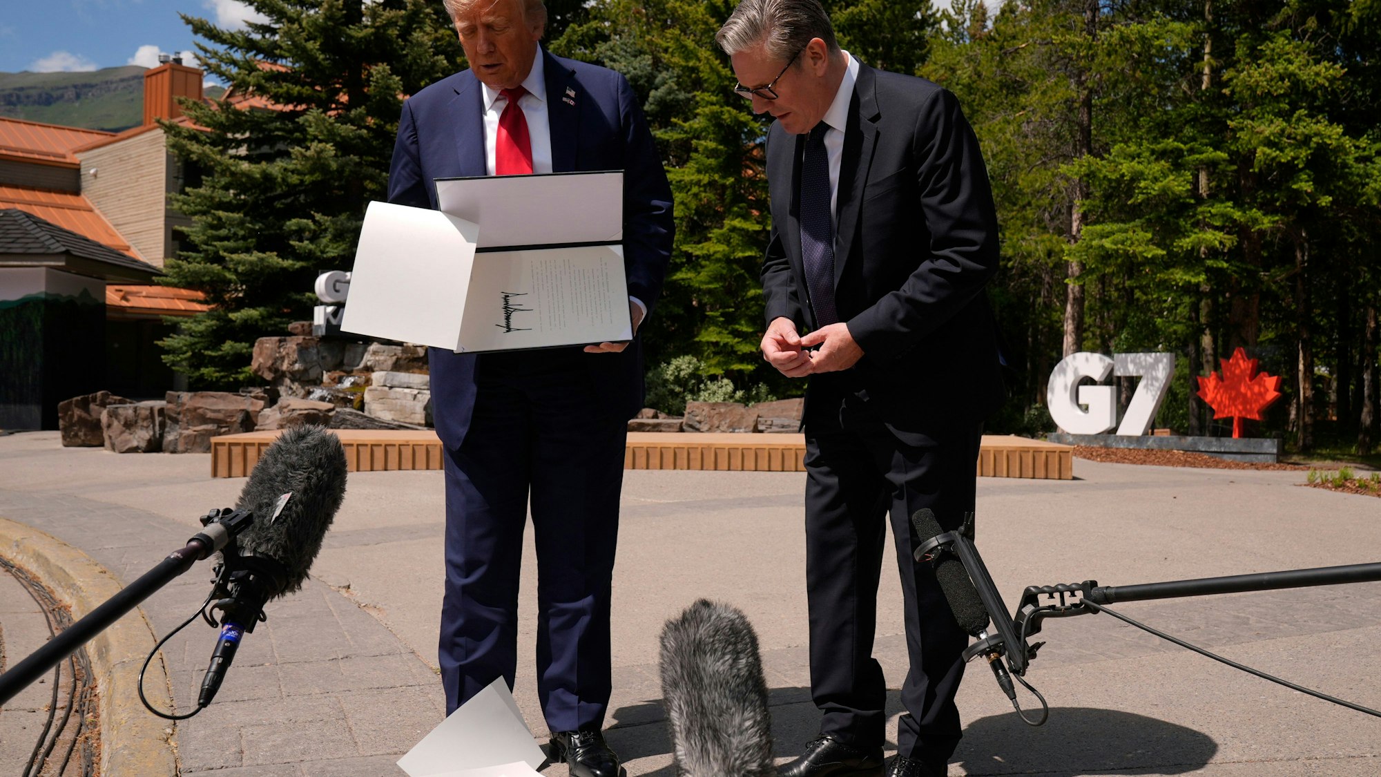 US-Präsident Donald Trump lässt Papiere fallen, als er am Rande des G7-Gipfels mit dem britischen Premierminister Keir Starmer zusammentrifft.