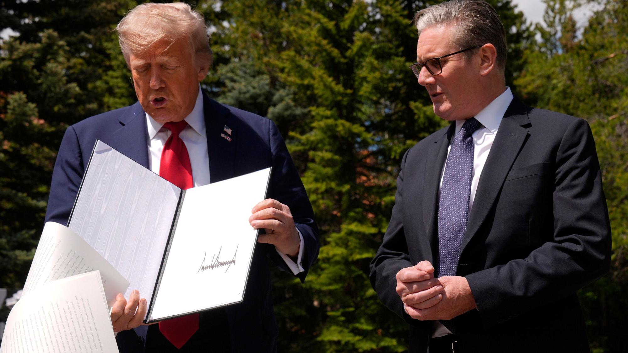 US-Präsident Donald Trump lässt Papiere fallen, als er am Rande des G7-Gipfels mit dem britischen Premierminister Keir Starmer zusammentrifft.