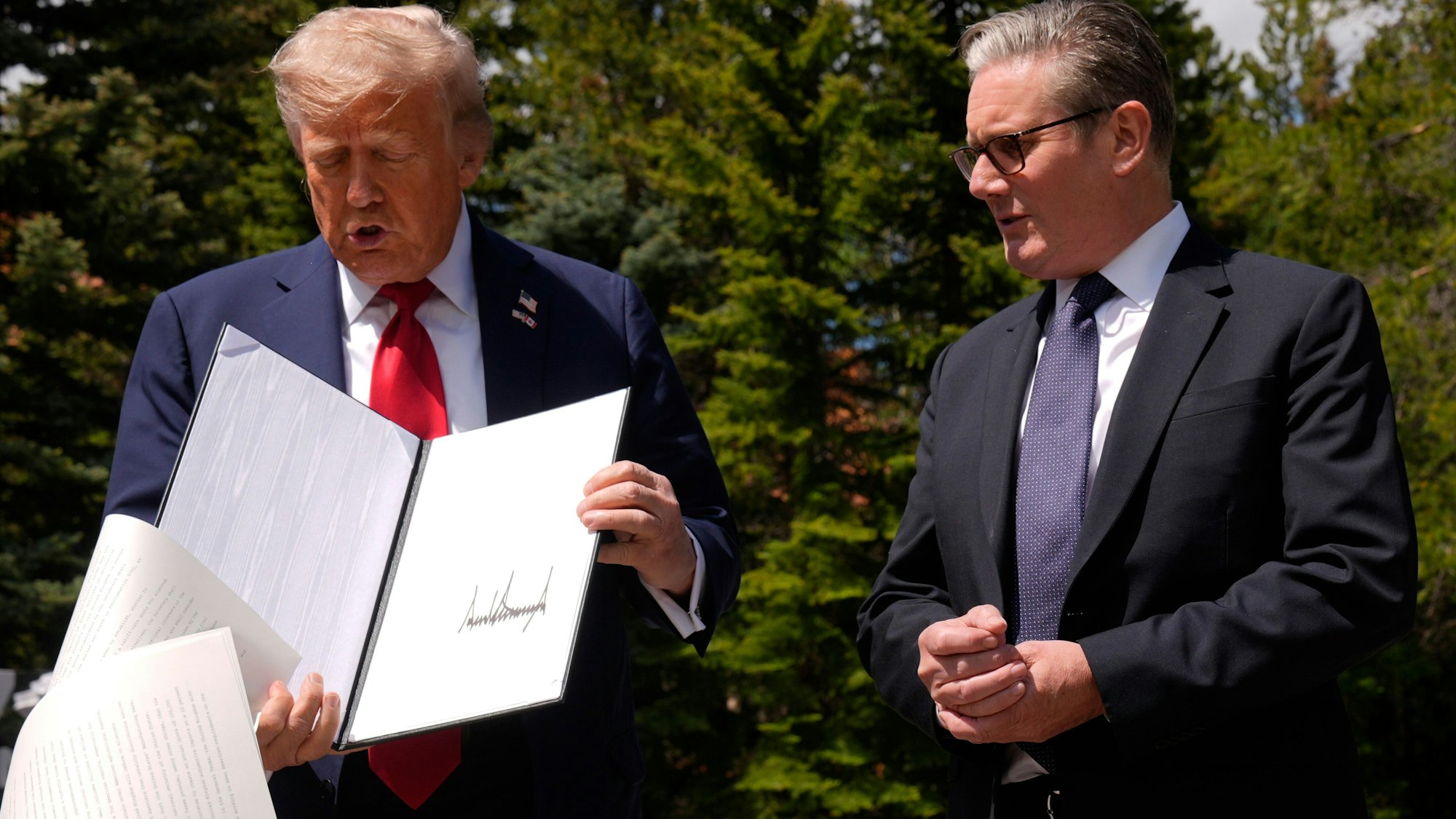 US-Präsident Donald Trump lässt Papiere fallen, als er am Rande des G7-Gipfels mit dem britischen Premierminister Keir Starmer zusammentrifft.