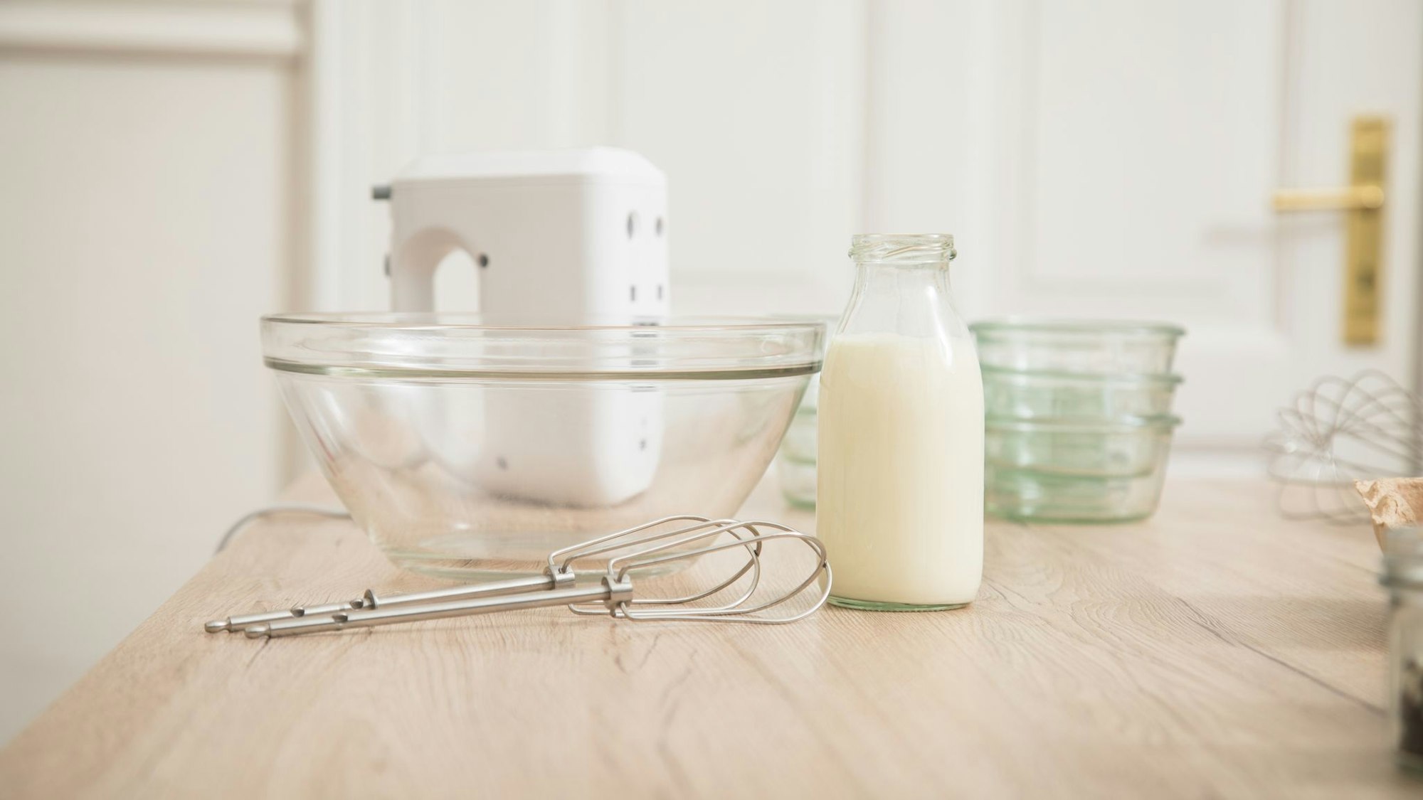 Eine Schüssel und Rührutensilien liegen auf einer Arbeitsplatte, neben der Schüssel steht eine Flasche Sahne.