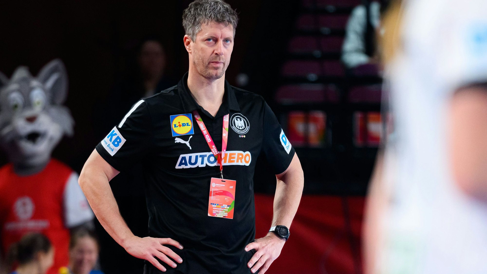 Markus Gaugisch blickt mit den Händen auf den Hüften Richtung Spielfeld.