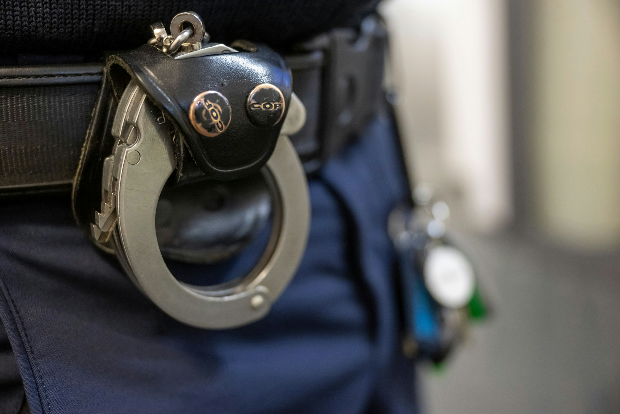 Das Bild zeigt Handschellen am Hosenbund eines Polizisten.