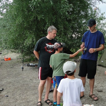 Kinder und Erwachsene stehen am Ufer eines Sees.