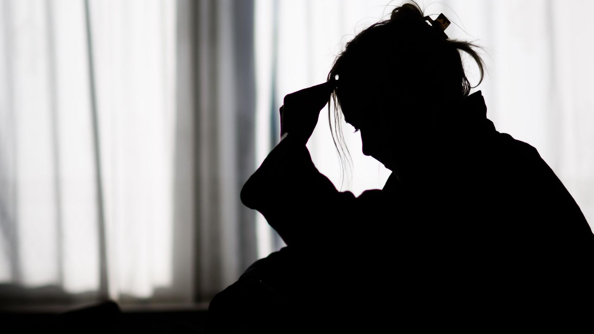 Das Foto zeigt die Silhouette einer Frau vor einer hellen Fensterfront.