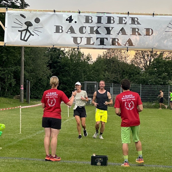 Christine Becker und Markus Habermann laufen nebeneinander ins Ziel, wo ein Mann und eine Frau in Biber-Backyard-T-Shirts warten.