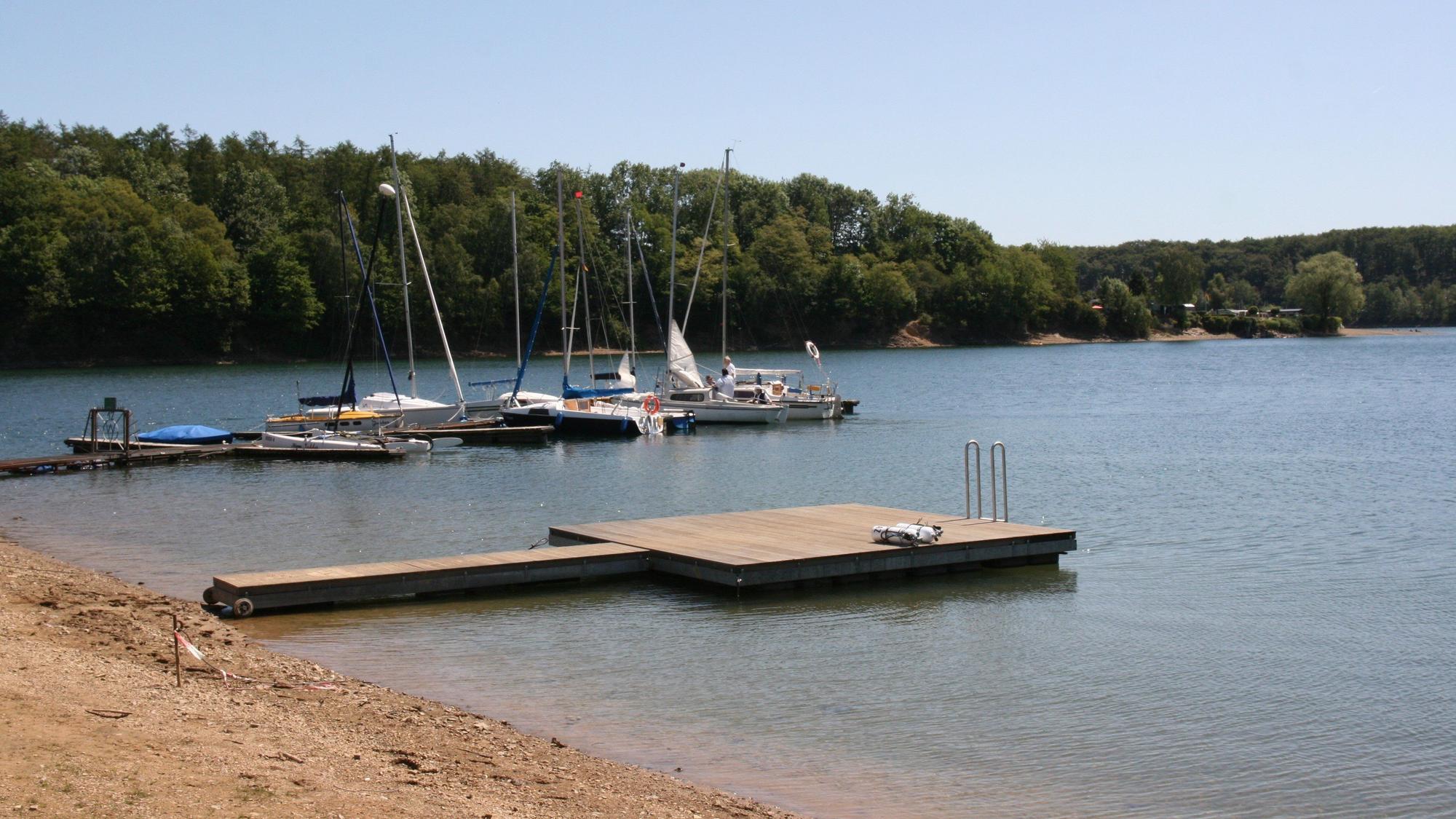 Ein Steg an Bevertalsperre in Hückeswagen, dahinter Boote.