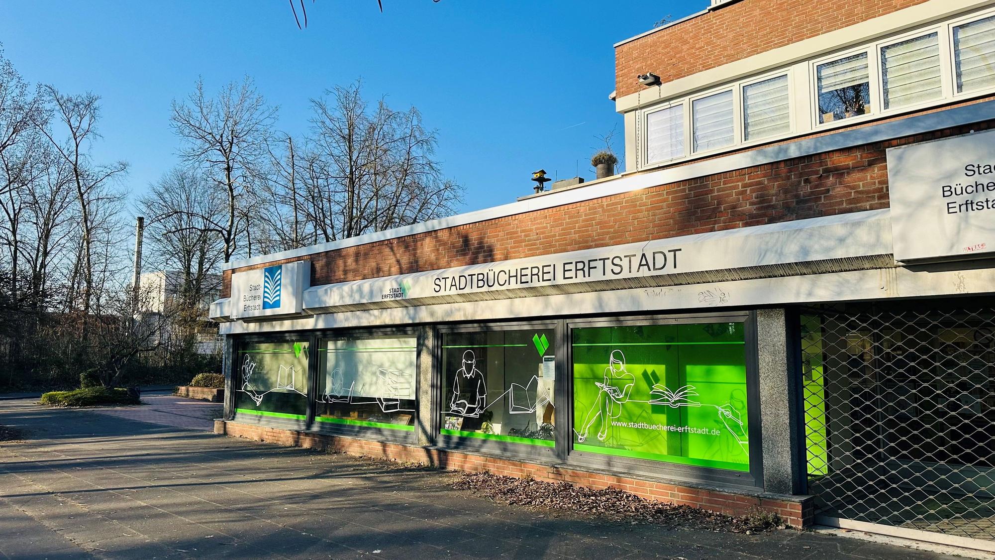 Zu sehen ist ein Gebäude aus Backstein mit einer großen Fensterfront vor blauem Himmel.
