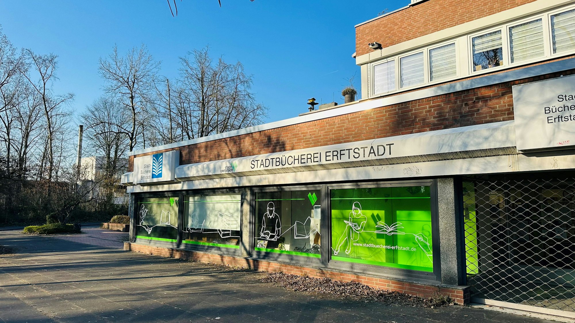 Zu sehen ist ein Gebäude aus Backstein mit einer großen Fensterfront vor blauem Himmel.