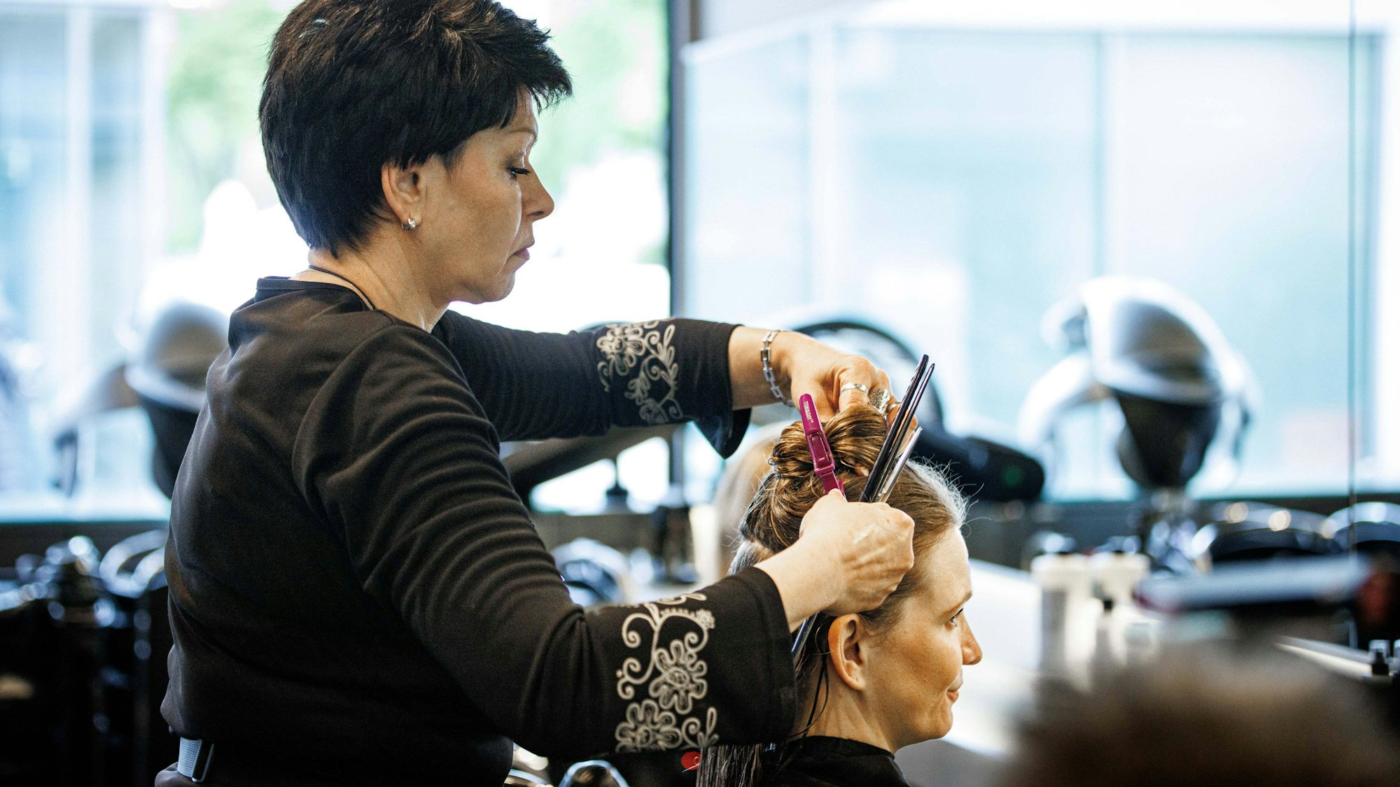 Valentyna Vysotska, Friseurin aus der Ukraine, steckt die Haare ihrer Kundin hoch, aufgenommen im Friseursalon Coiffeur Sivan in Berlin, 22.04.2024. Berlin Deutschland *** Valentyna Vysotska, hairdresser from Ukraine, puts up her customers hair, photographed in the hairdressing salon Coiffeur Sivan in Berlin, 22 04 2024 Berlin Germany Copyright: xJulianexSonntagxphotothek.dex