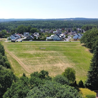 Die Drohnenaufnahme zeigt das geplante Baugebiet Am Rothenloch, das am Ortsrand von Satzvey (im Hintergrund) in Richtung Firmenich entstehen soll.