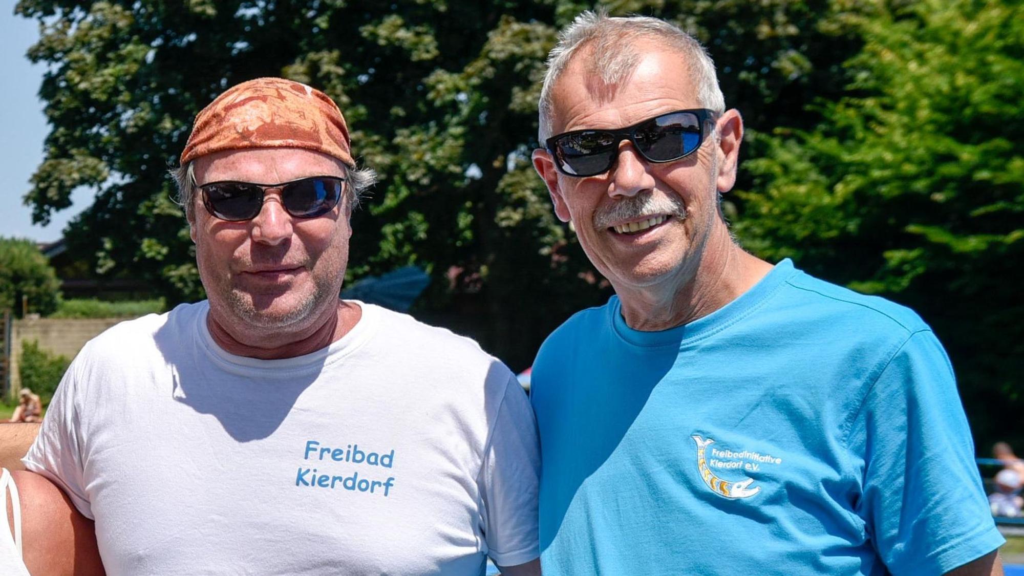 Zwei Männer mit Sonnenbrillen stehen im Grünen.