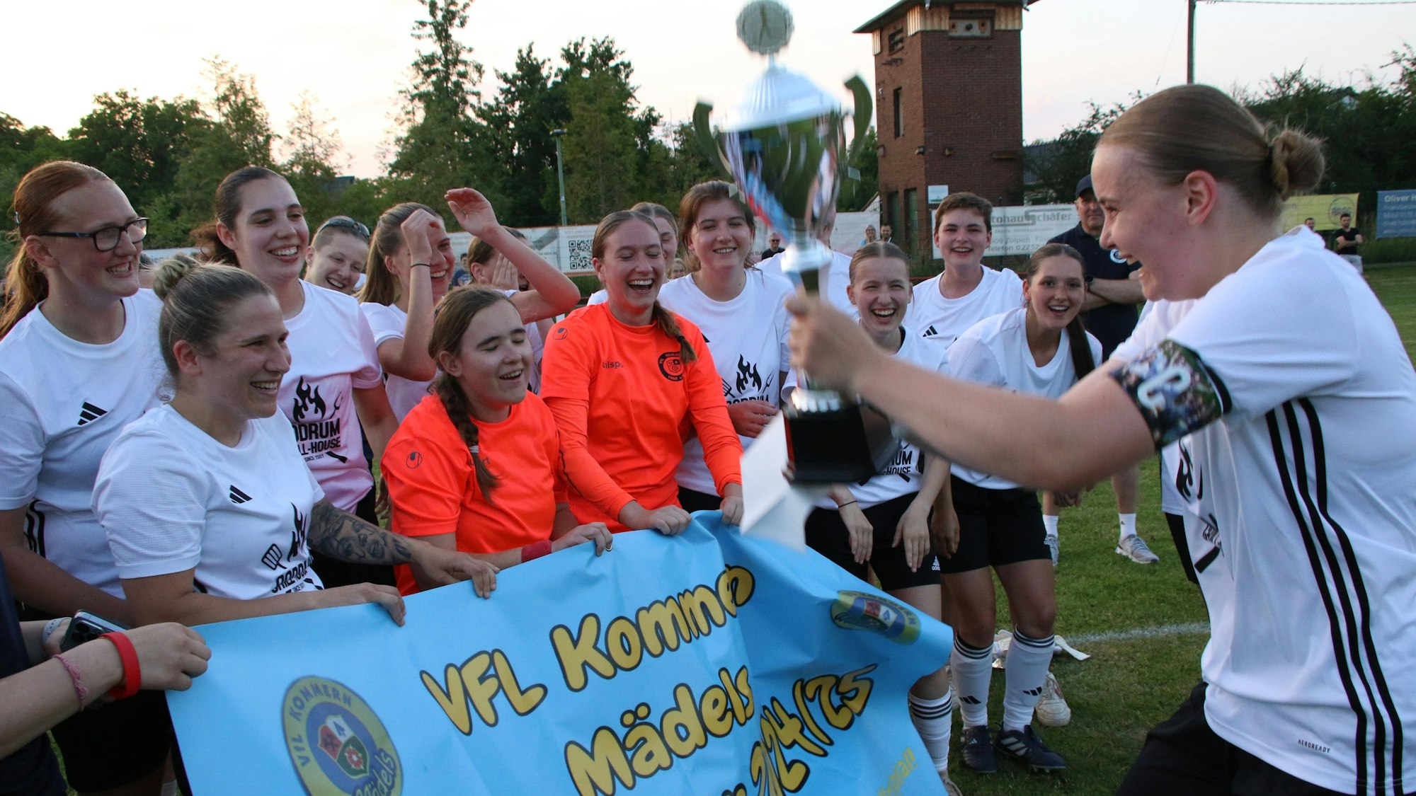 Kapitänin Nele Wagner hält den Pokal in die Höhe und zeigt ihn ihren jubelnden Mitspielerinnen.