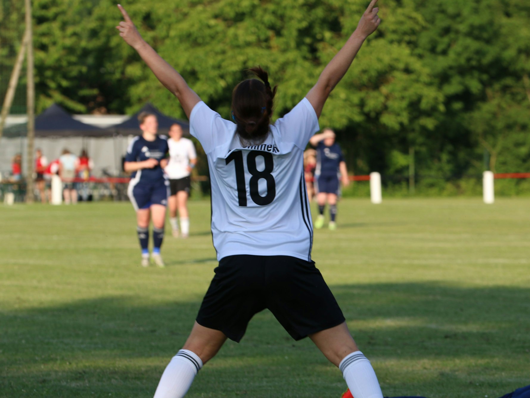 Breitbeinig und mit in den Himmel gestreckten Zeigefingern steht Helene Esser mit dem Rücken zum Fotografen und jubelt über ihr Tor.