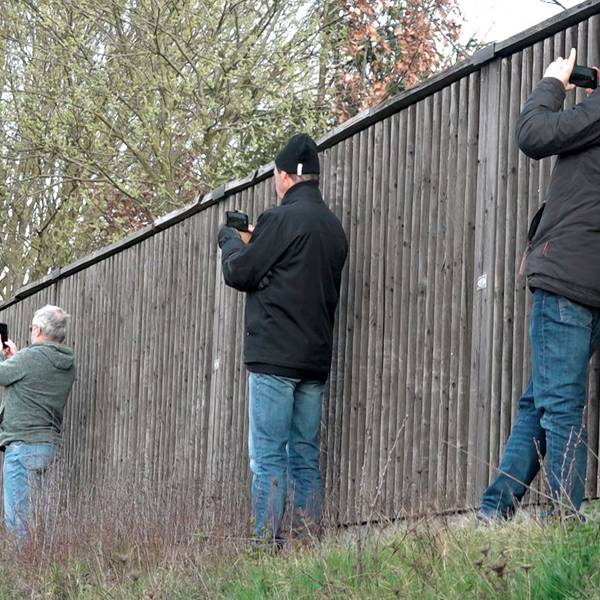 Schaulustige fotografieren neben einer Lärmschutzwand mit ihren Smartphones eine Unfallstelle.