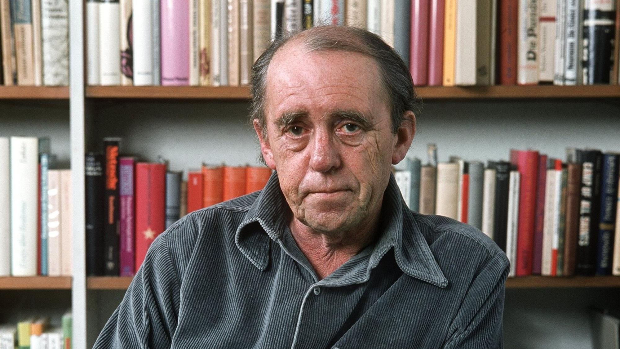 Der Schriftsteller Heinrich Böll sitzt vor einem Bücherregal in seiner Kölner Wohnung im Dezember 1977.