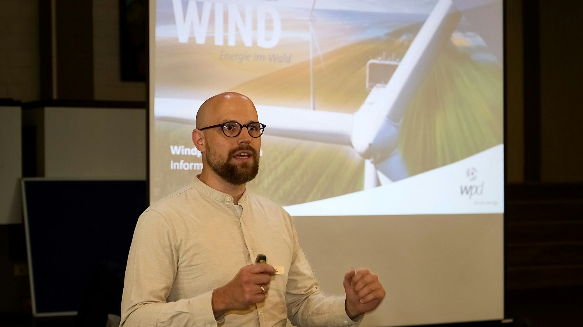 Johannes Weisensee steht vor einem an eine Wand projizierten Bild eines Windrades.