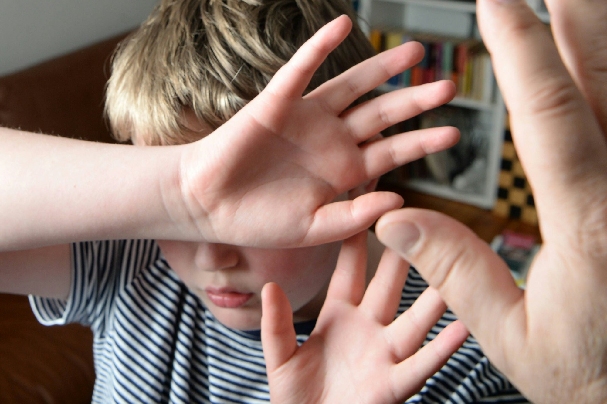 Ein Junge versucht sich vor den Schlägen seines Vaters zu schützen, indem er seine Hände vor sein Gesicht hält.
