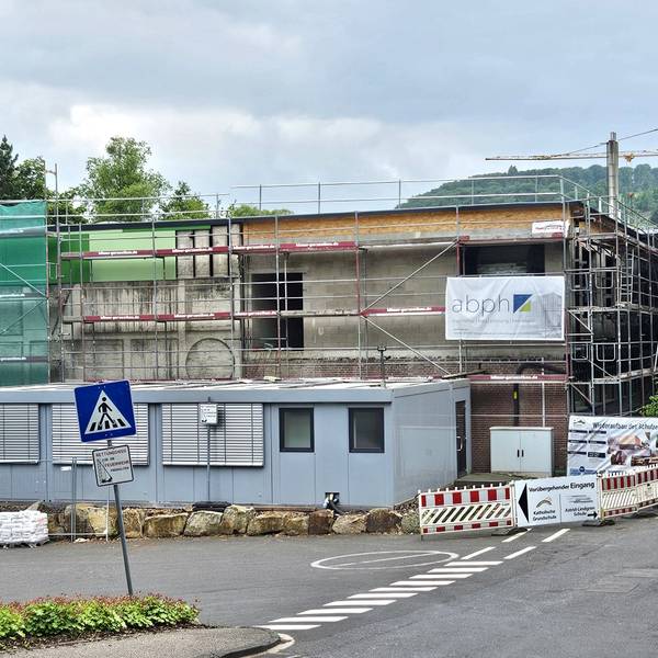 Blick auf die eingerüstete Turnhalle. Im Hintergrund ist ein Kran zu sehen.