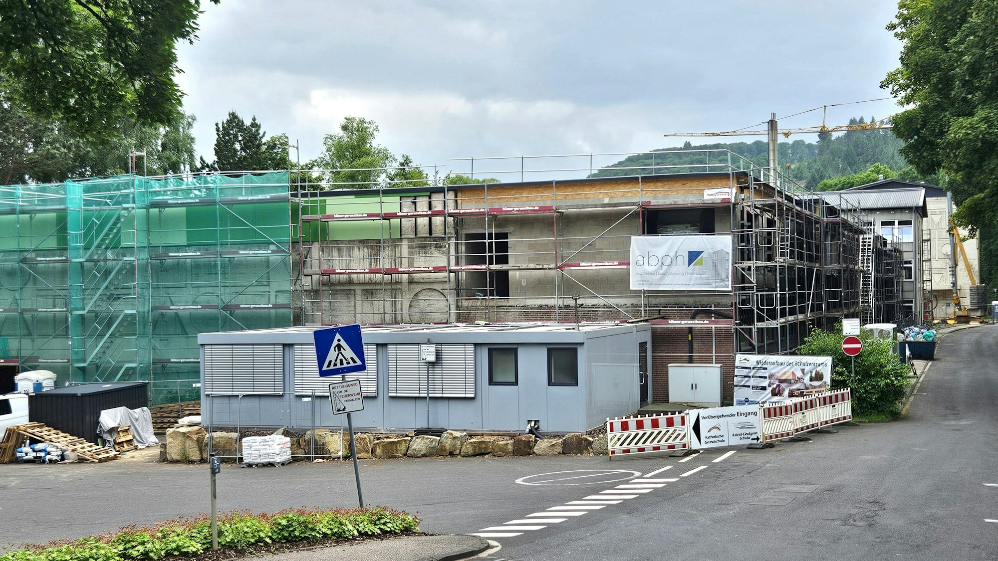 Blick auf die eingerüstete Turnhalle. Im Hintergrund ist ein Kran zu sehen.