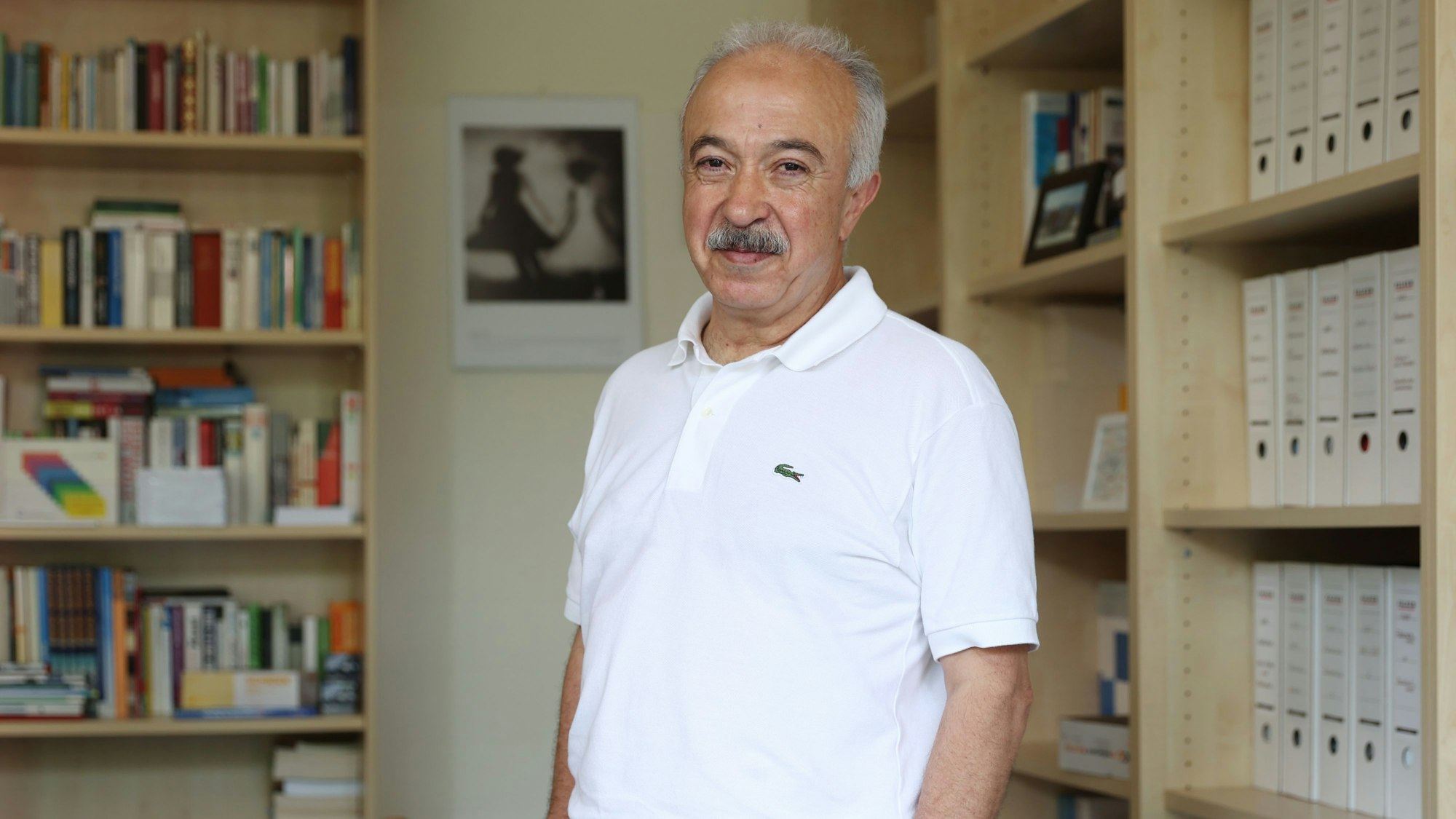 Rufai Karakaya im Büro des Berufskollegs Südstadt. Er lächelt freundlich in die Kamera.