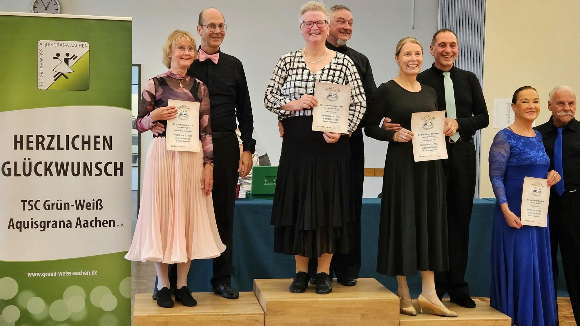 Uwe und Vera Bartsch stehen auf dem Podium ganz oben. Vera Bartsch hält die Urkunde in die Kamera.