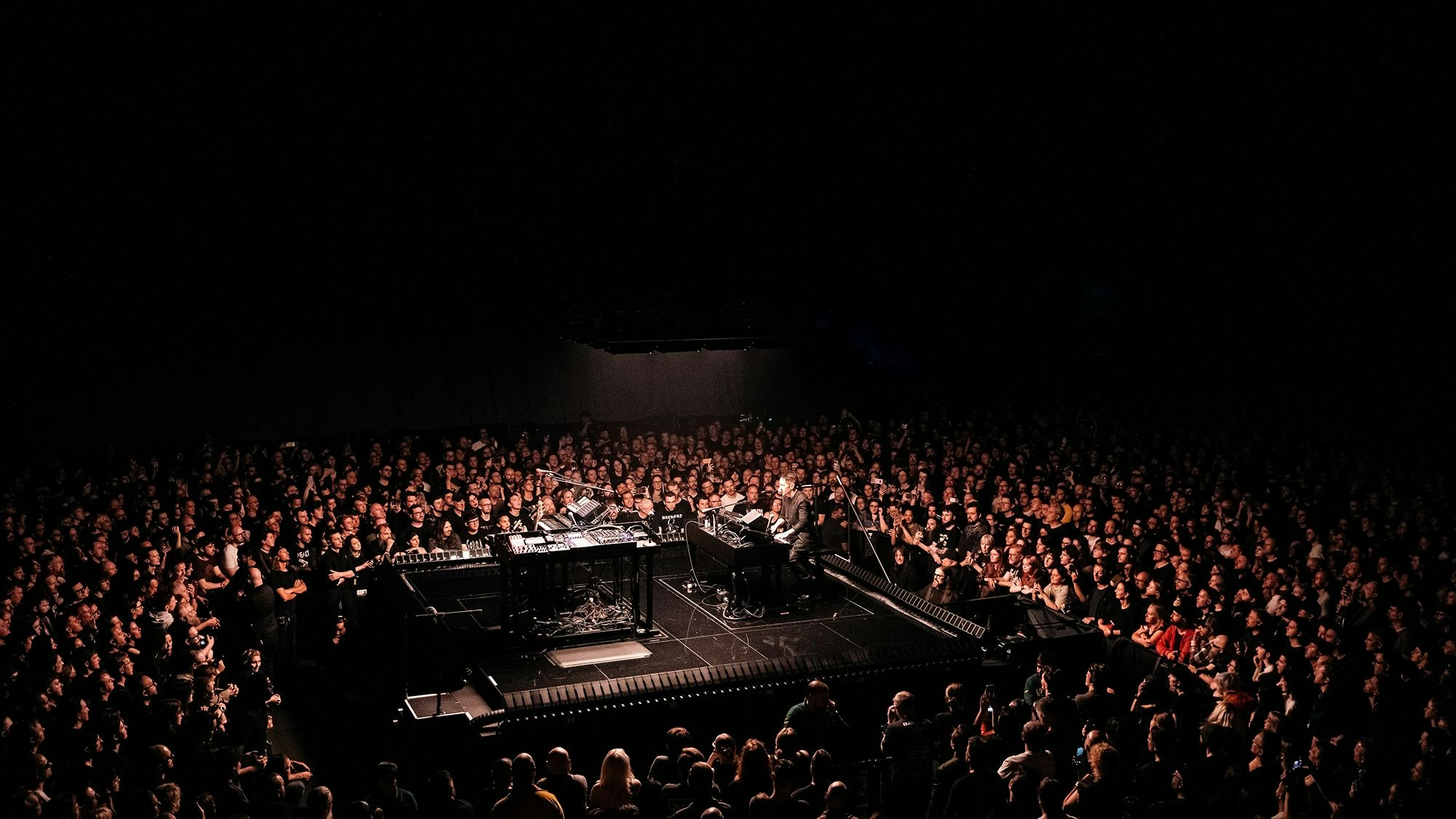 Trent Reznor sitz auf einer kleinen Bühne allein am elektrischen Klavier, umringt von Fans