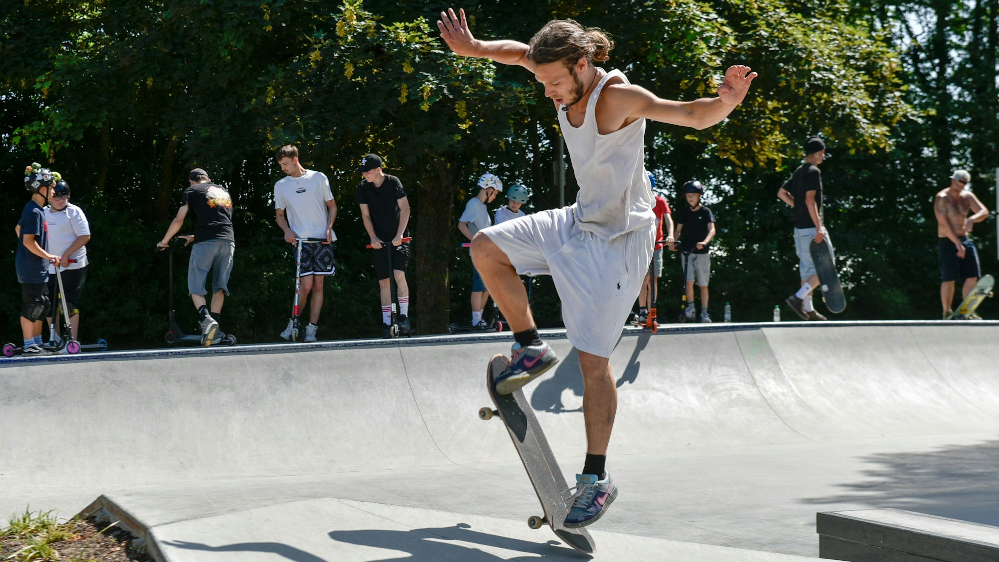 Zu sehen ist ein junger Mann, der einen Trick mit seinem Skateboard versucht.