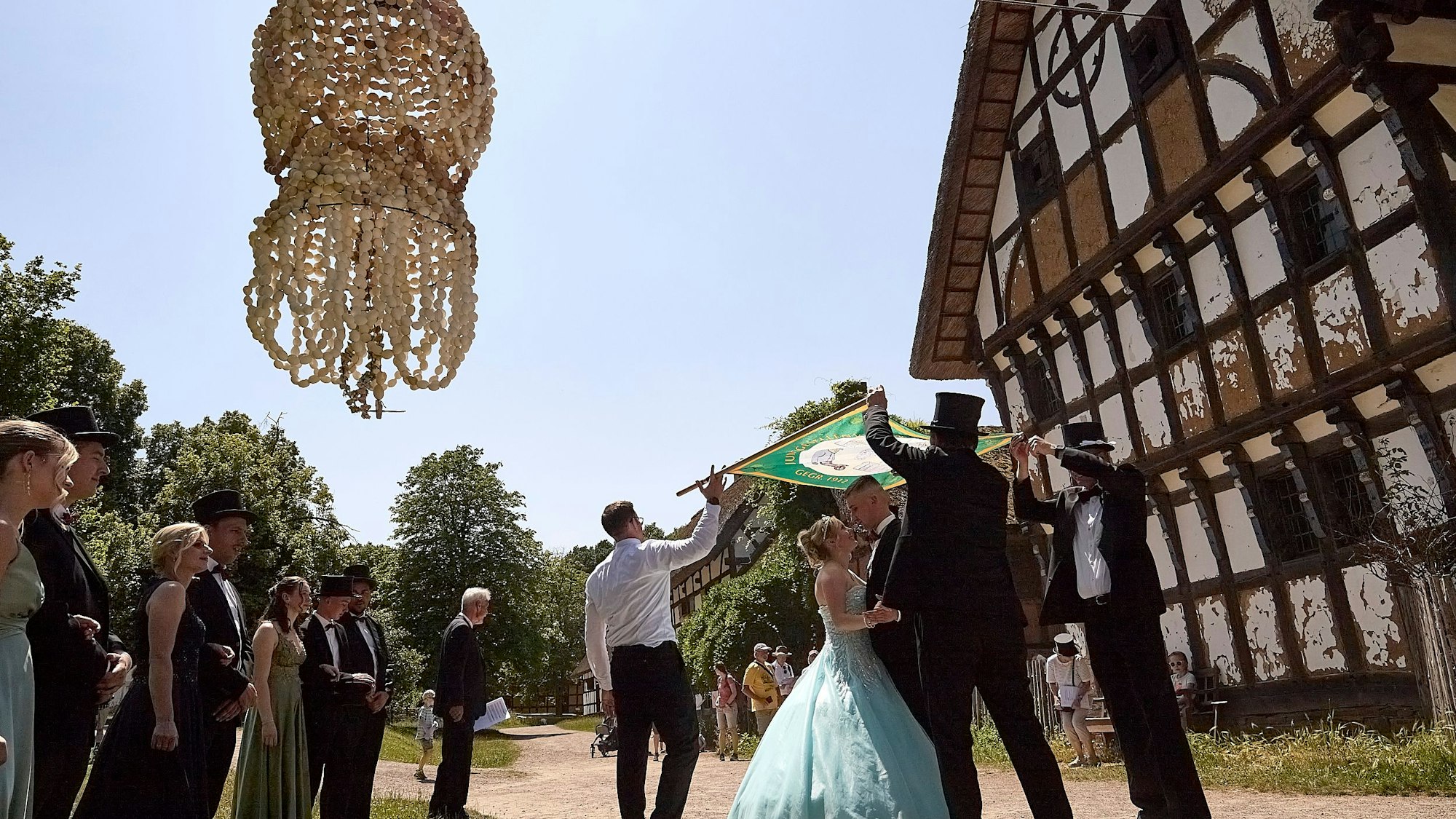 Das Bild zeigt das Maikönigspaar tanzend vor einem historischen Gebäude. Die Eierkrone hängt über den beiden in der Luft.