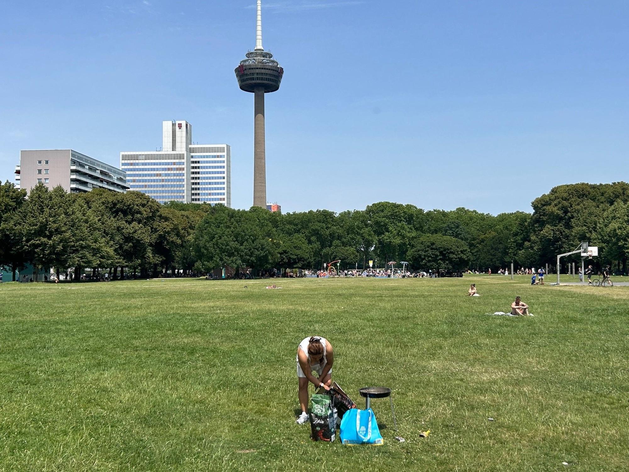 Kein Schatten unterm Colonius: eine einsame Grillerin bereitet bei 35 Grad die Holzkohle vor.