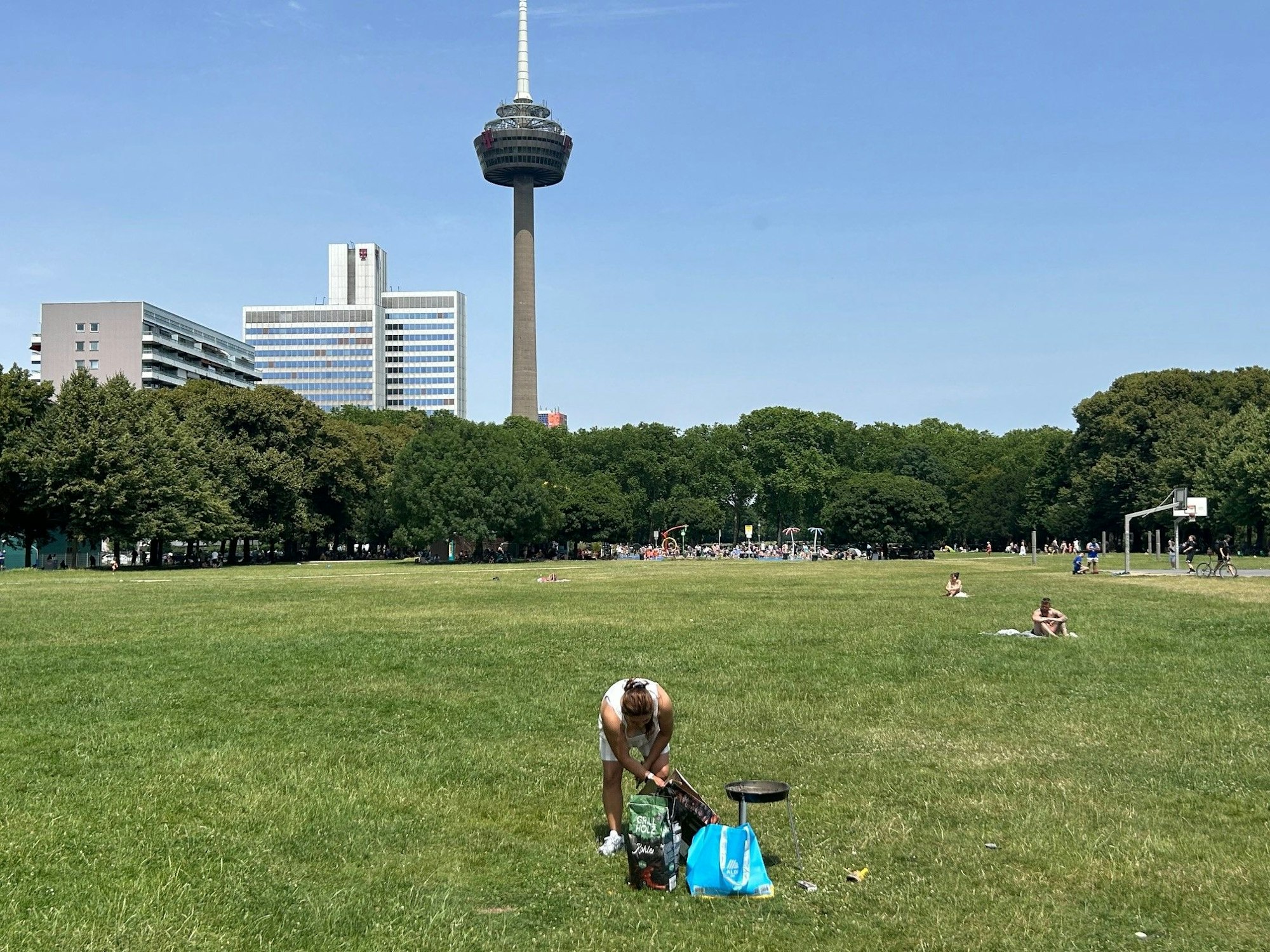 Kein Schatten unterm Colonius: eine einsame Grillerin bereitet bei 35 Grad die Holzkohle vor.