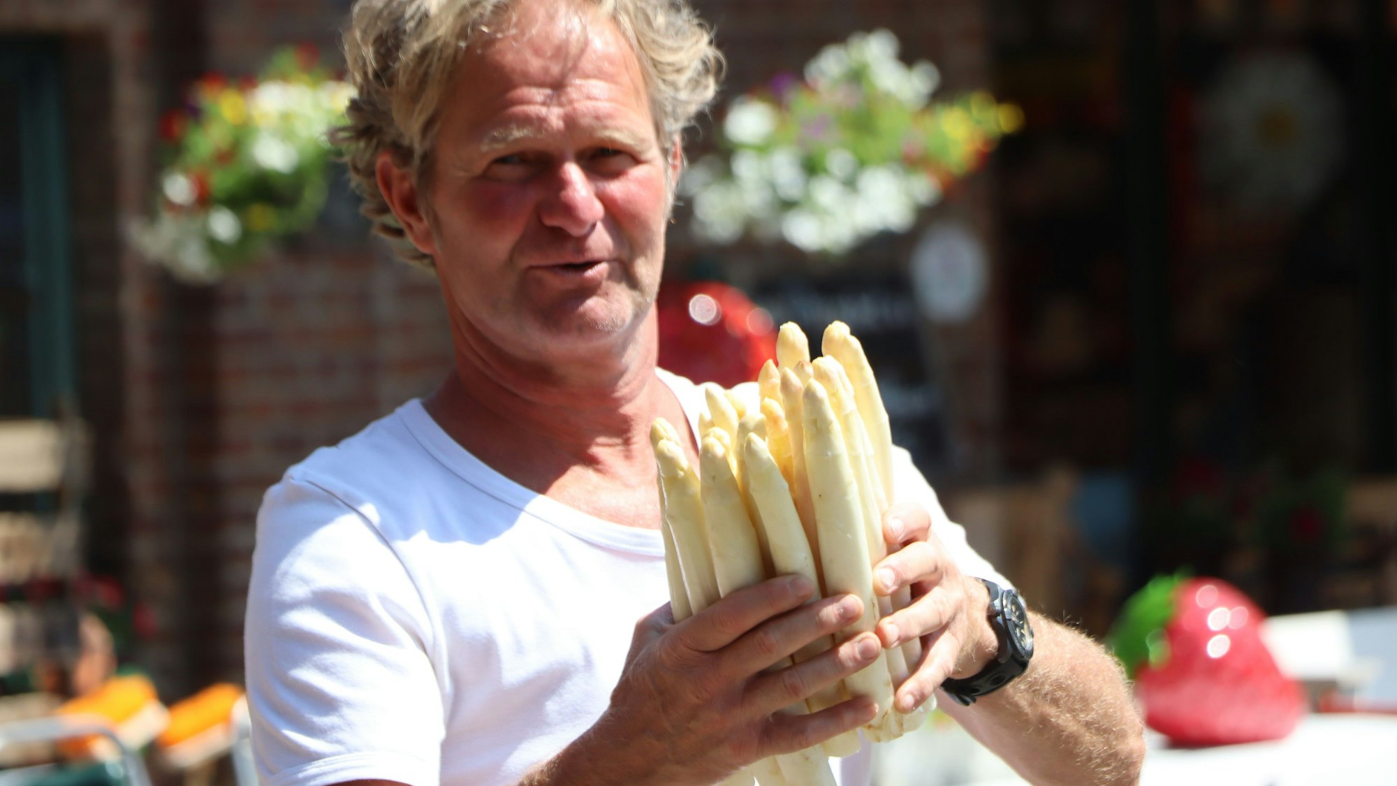 Auf dem Bild ist ein Landwirt zu sehen, der Spargel in den Händen hält.