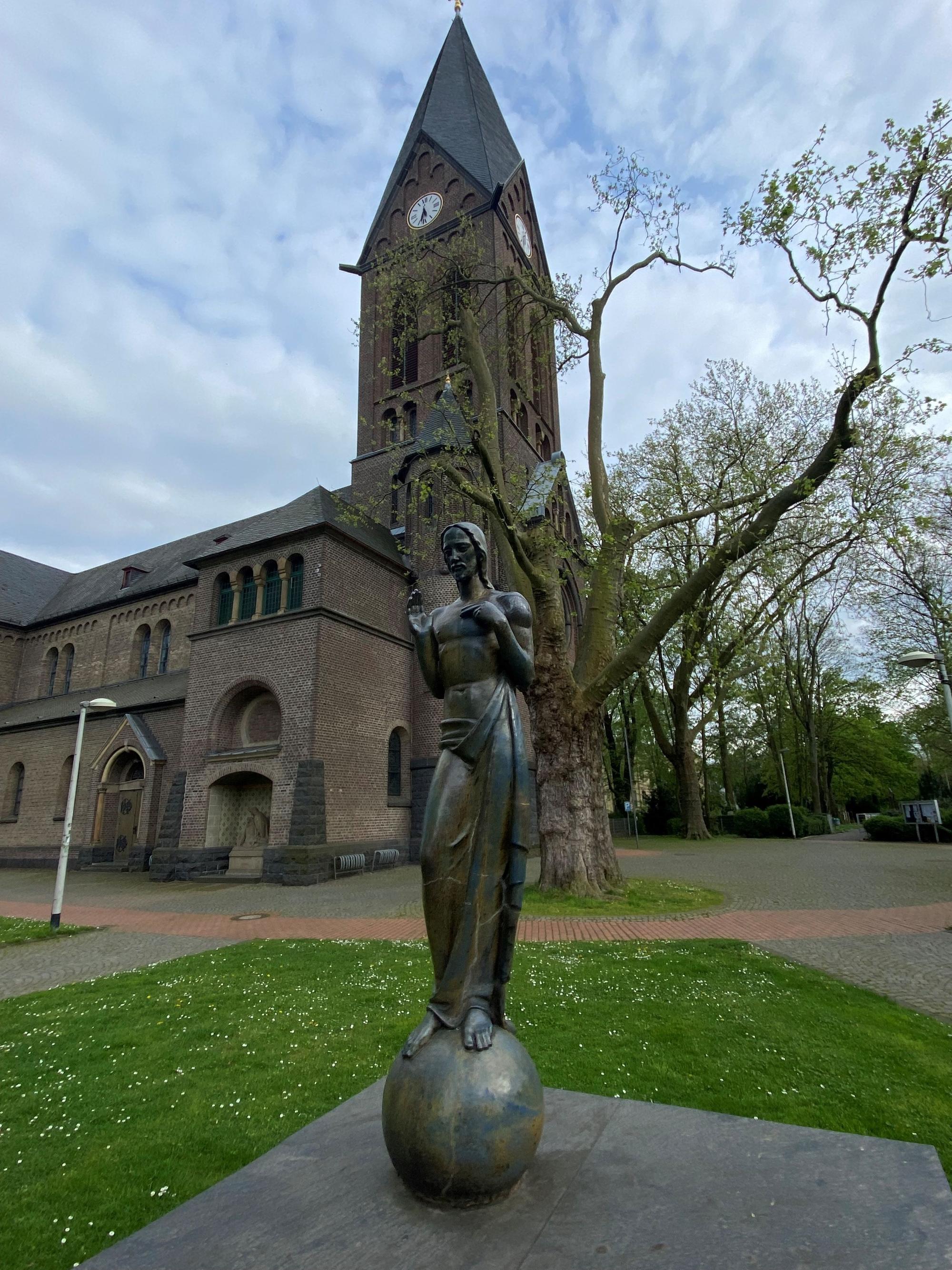 Auf dem Bild ist eine Skulptur vor einer Kirche zu sehen.