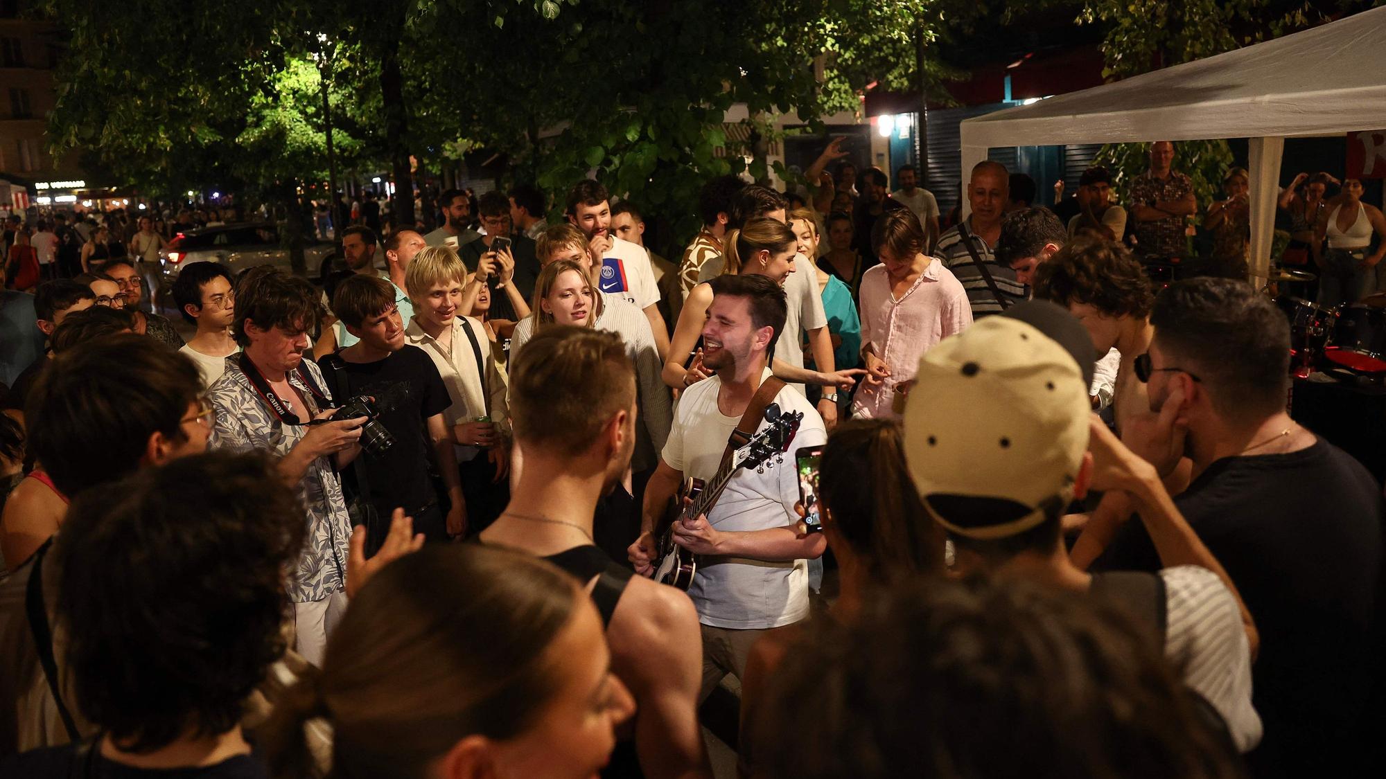 Musikbegeisterte lauschen einem Mann, der während des jährlichen französischen Straßenmusikfestivals "Fete de la Musique" im 4. Arrondissement von Paris Gitarre spielt.